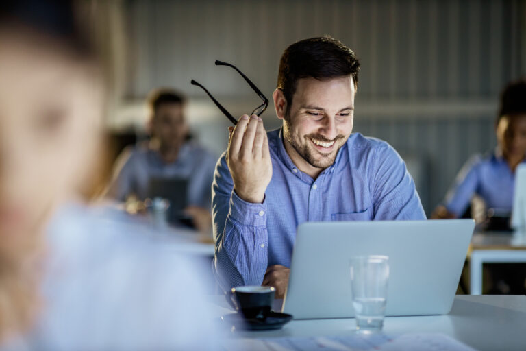 happy male entrepreneur reading an e mail on a computer during education event in the office.